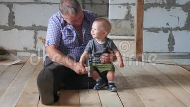 在工地上工作的爷爷和孙子。祖父教他的孙子锤钉子